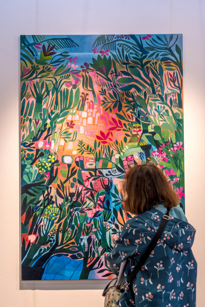 A woman admiring a painting at Affordable Art Fair