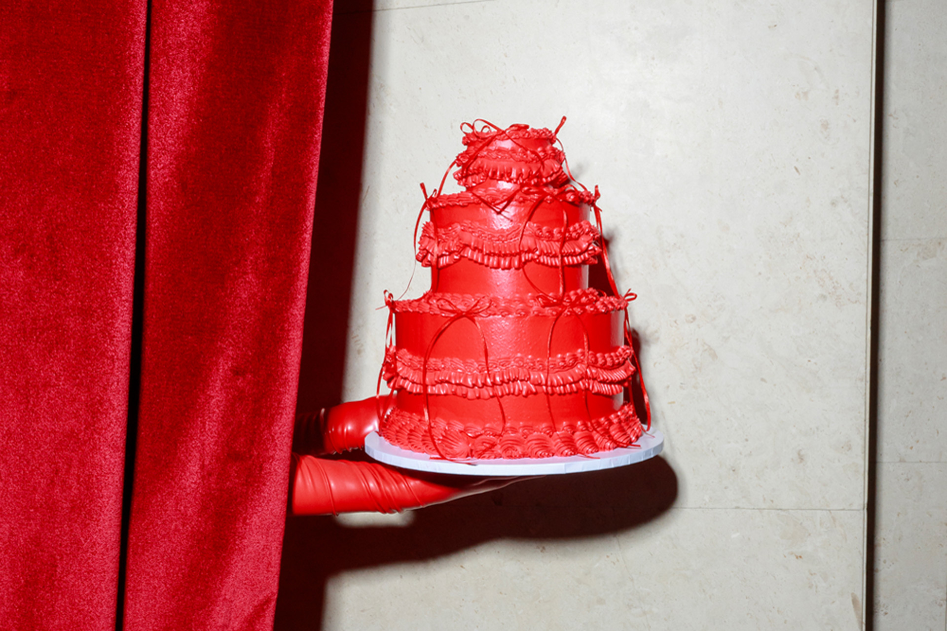 Red hand holding up a red cake