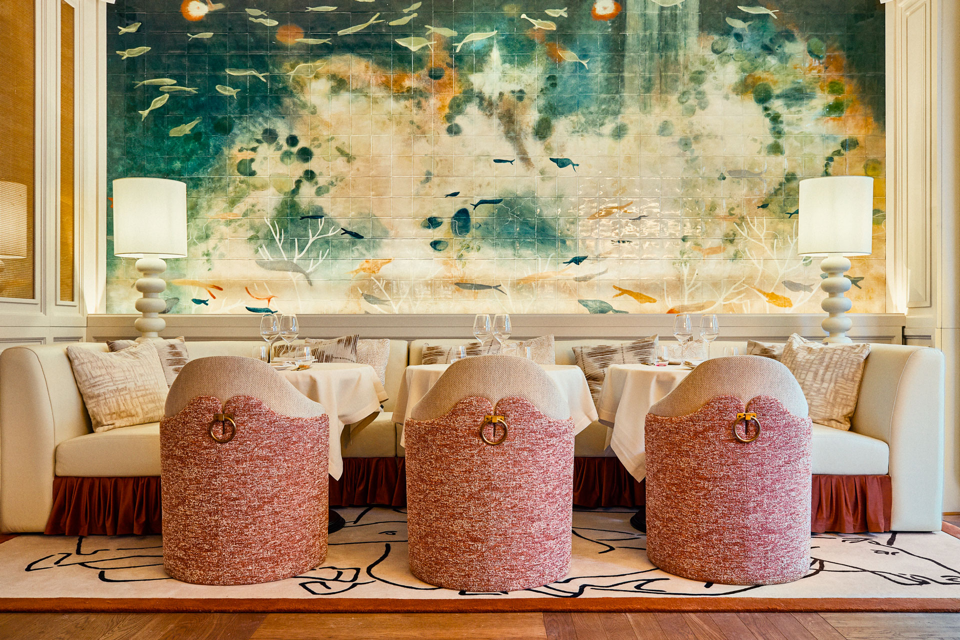 Three pink chairs set around a dining booth in La Baia