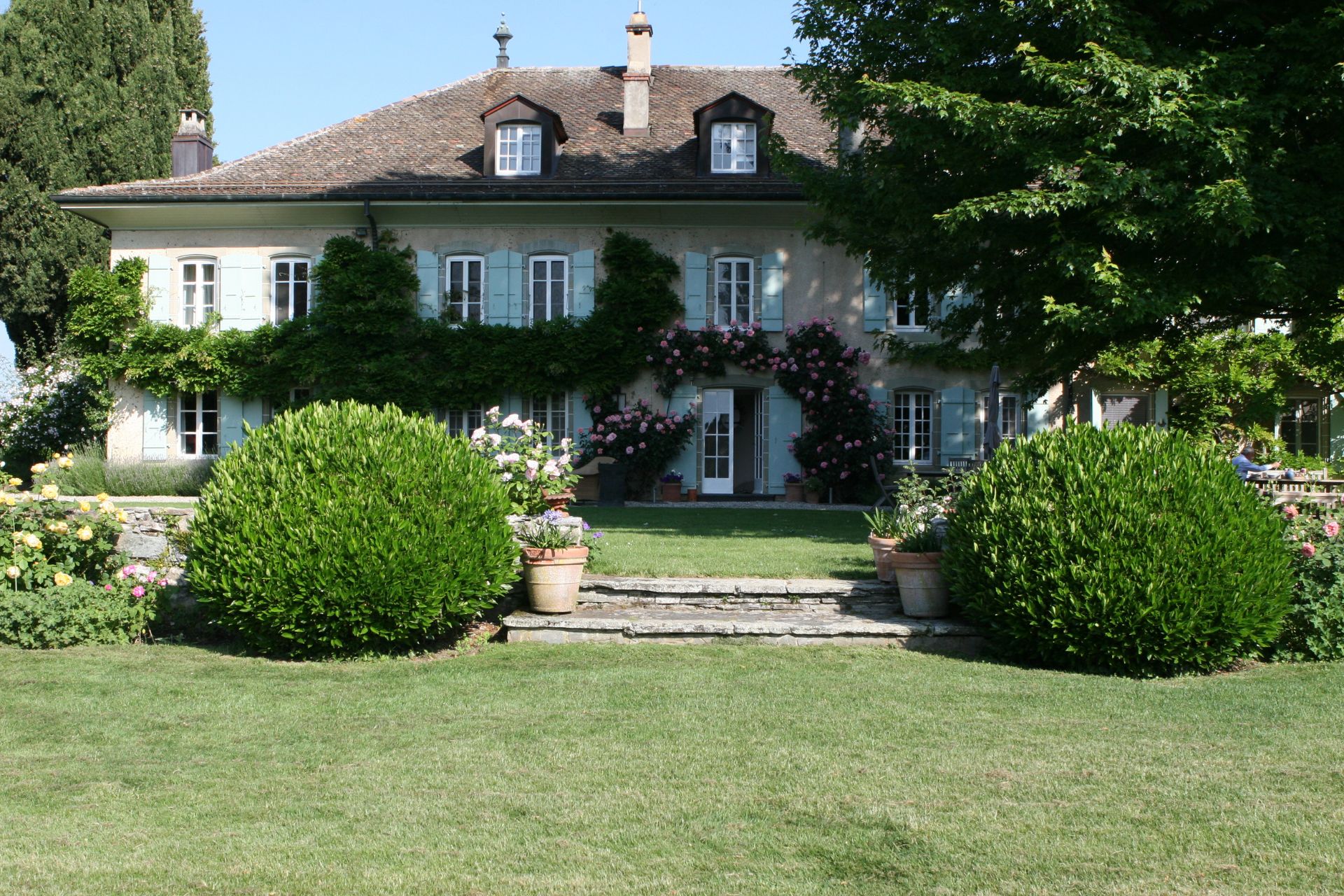 Swiss villa with landscaped bushes and rose trellises.