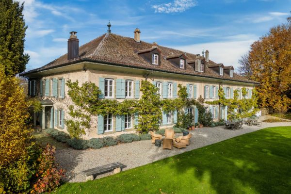 Swiss villa with wisteria-clad facade and pale blue shutters.