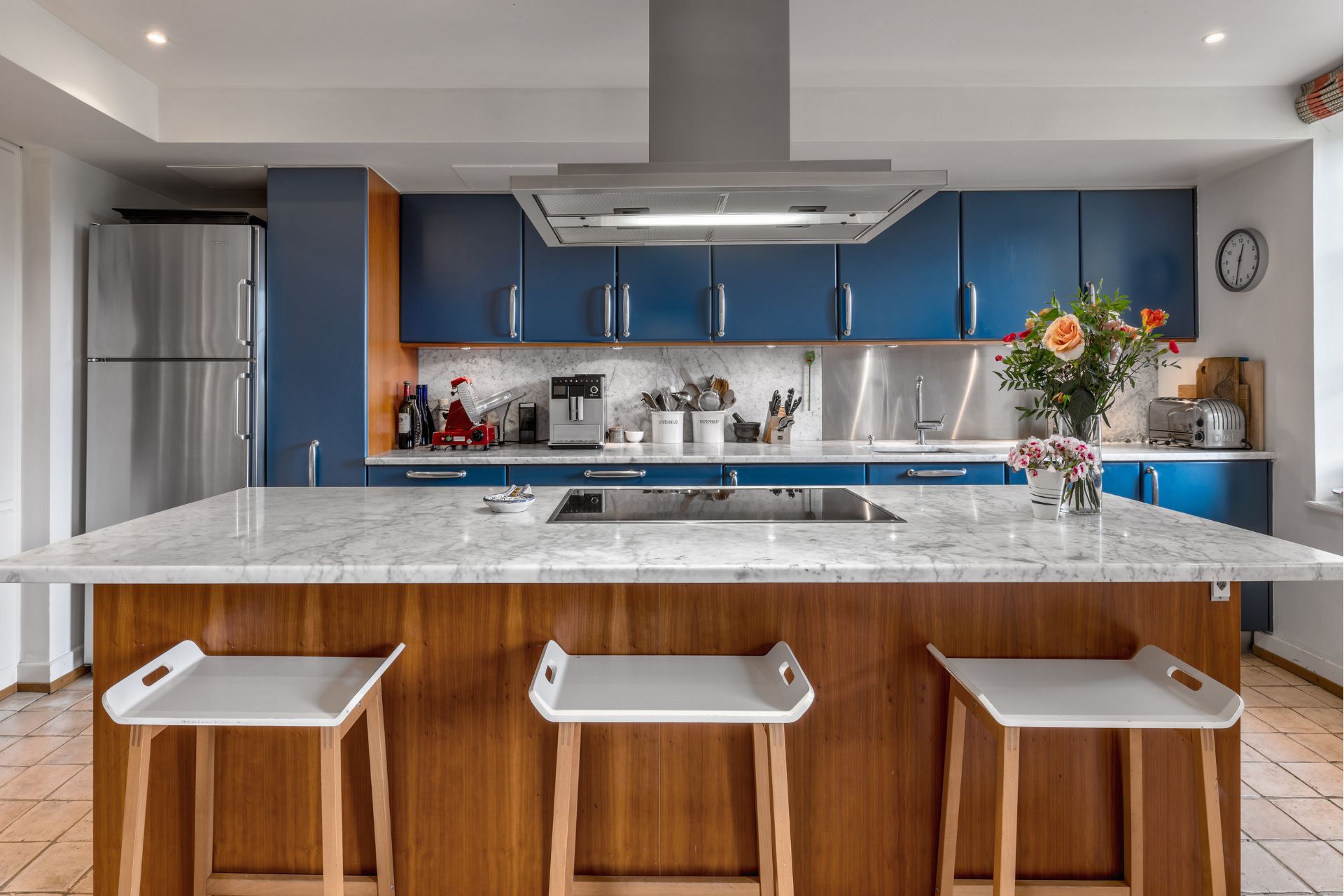 Kitchen with navy cabinets, a dark wooden island and white marble worktops.