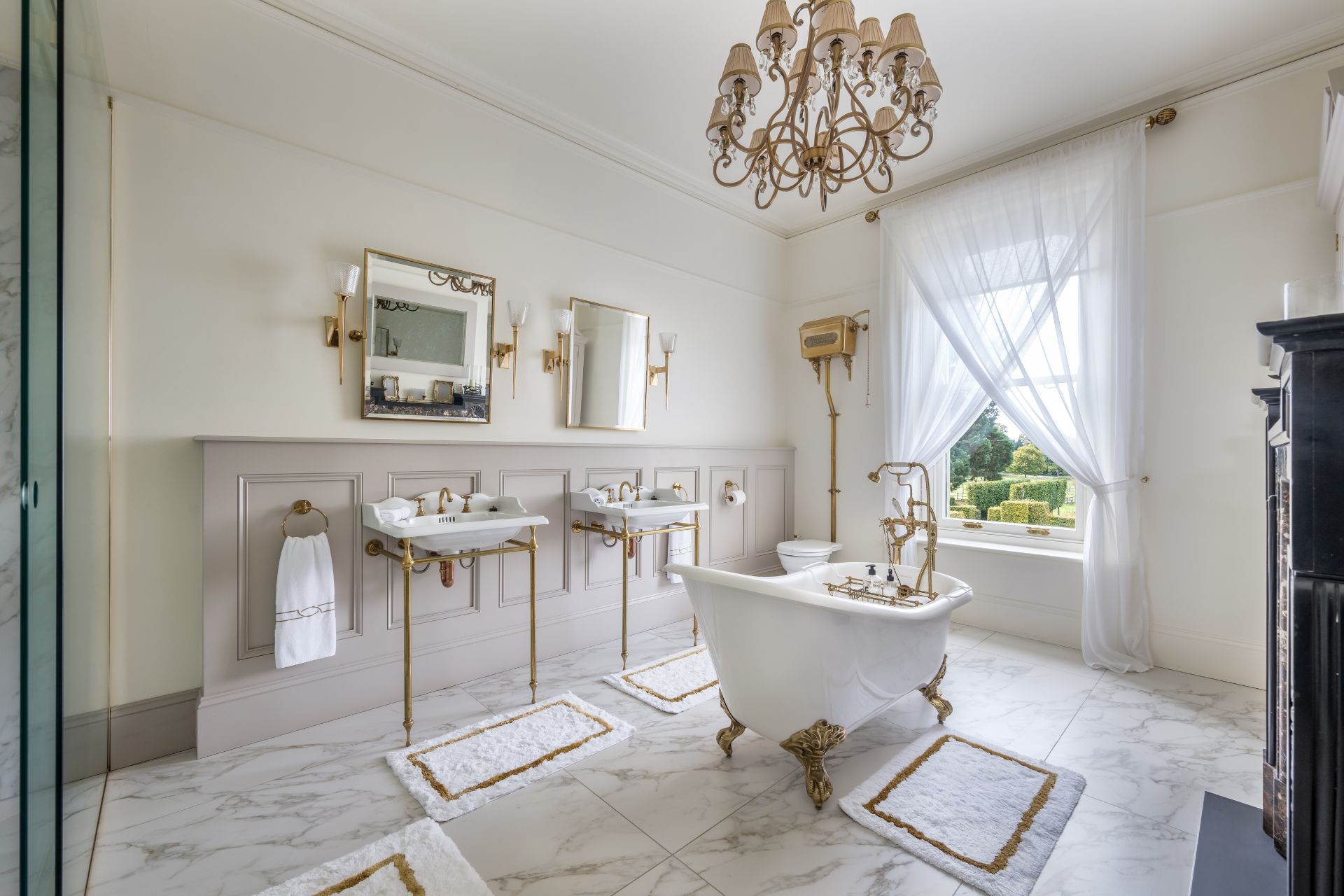 Marble bathroom with a freestanding bathtub, two sinks and a large sash window