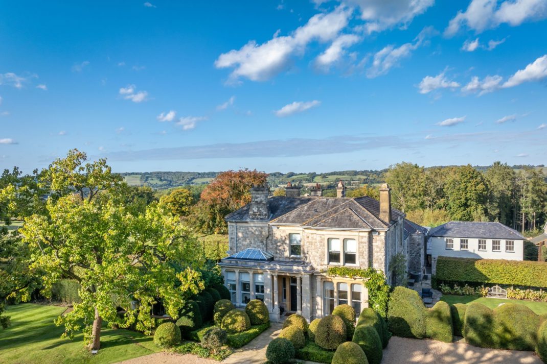 Aerial view of stone country house on a large, leafy estate