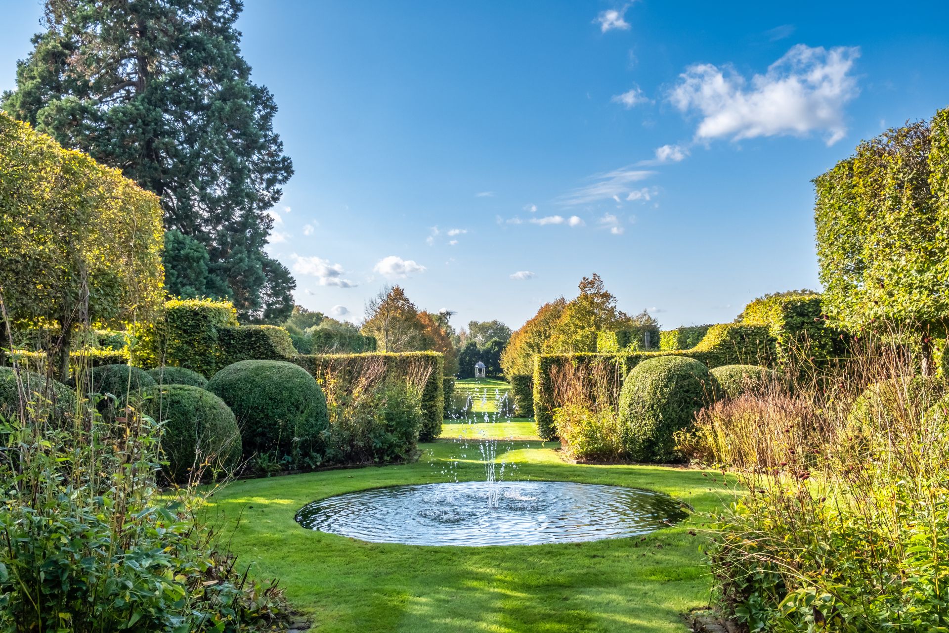 Garden with circular pond, water fountain and landscaped hedges