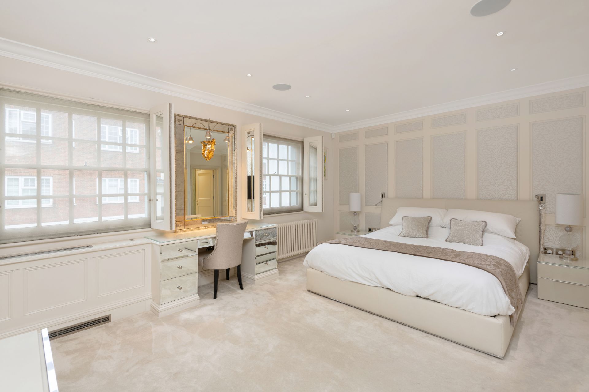 Bedroom with cream carpets, grey and cream wall pannelling and white bedding.