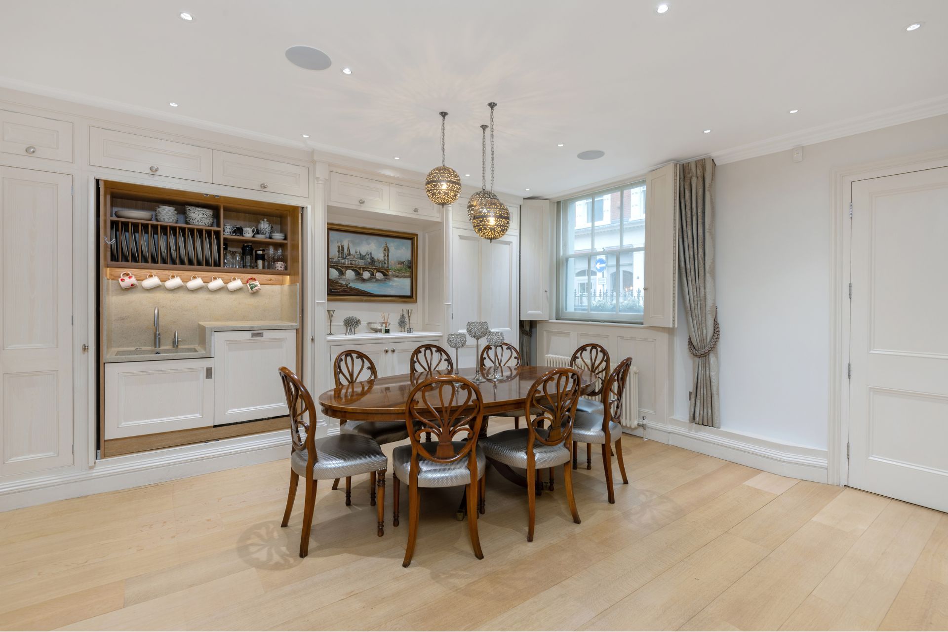 Kitchen with pale wood floors, mahogany furniture and white cabinets.