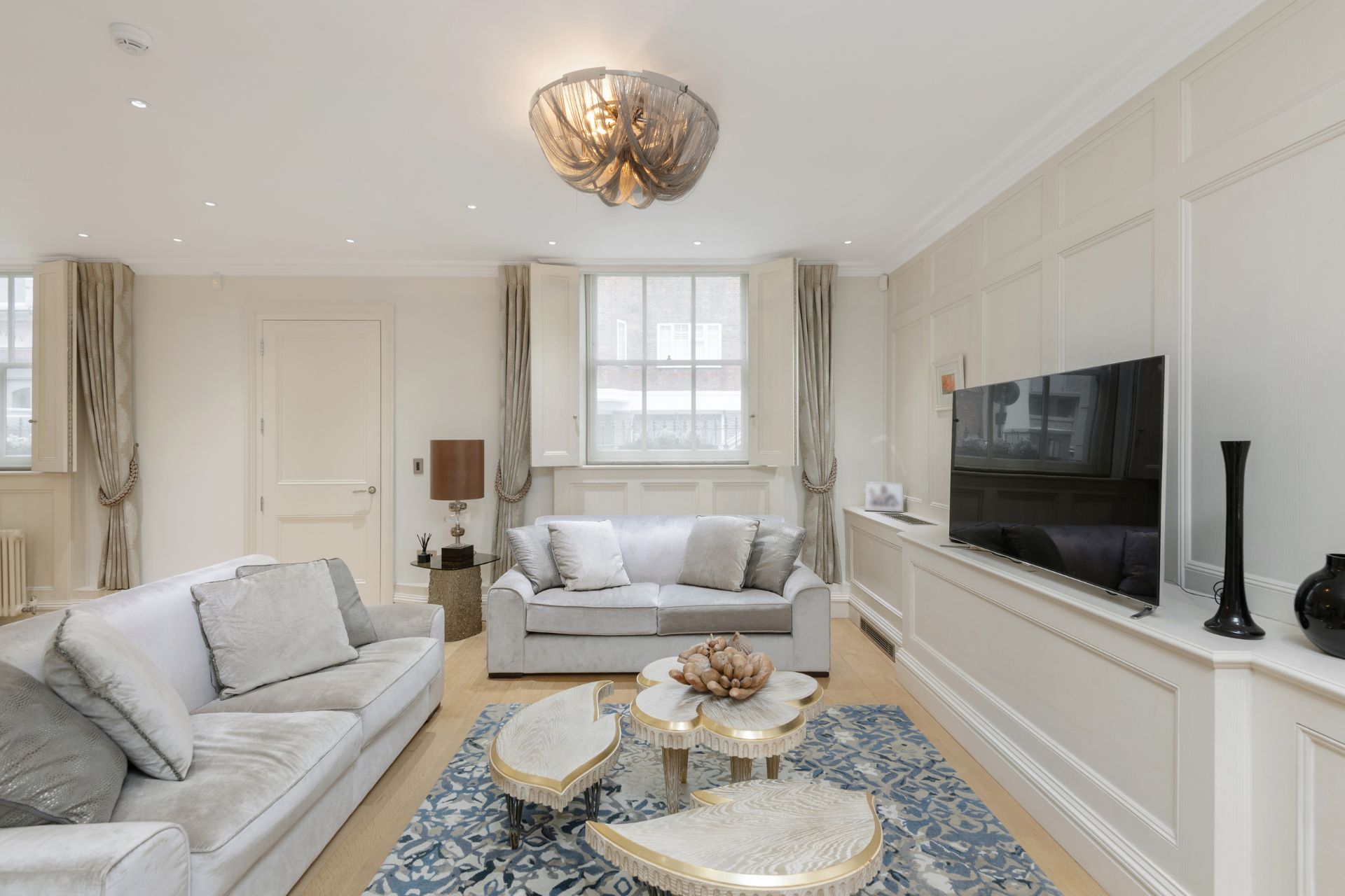Living room with cream sofas, white cabinets and a large TV.