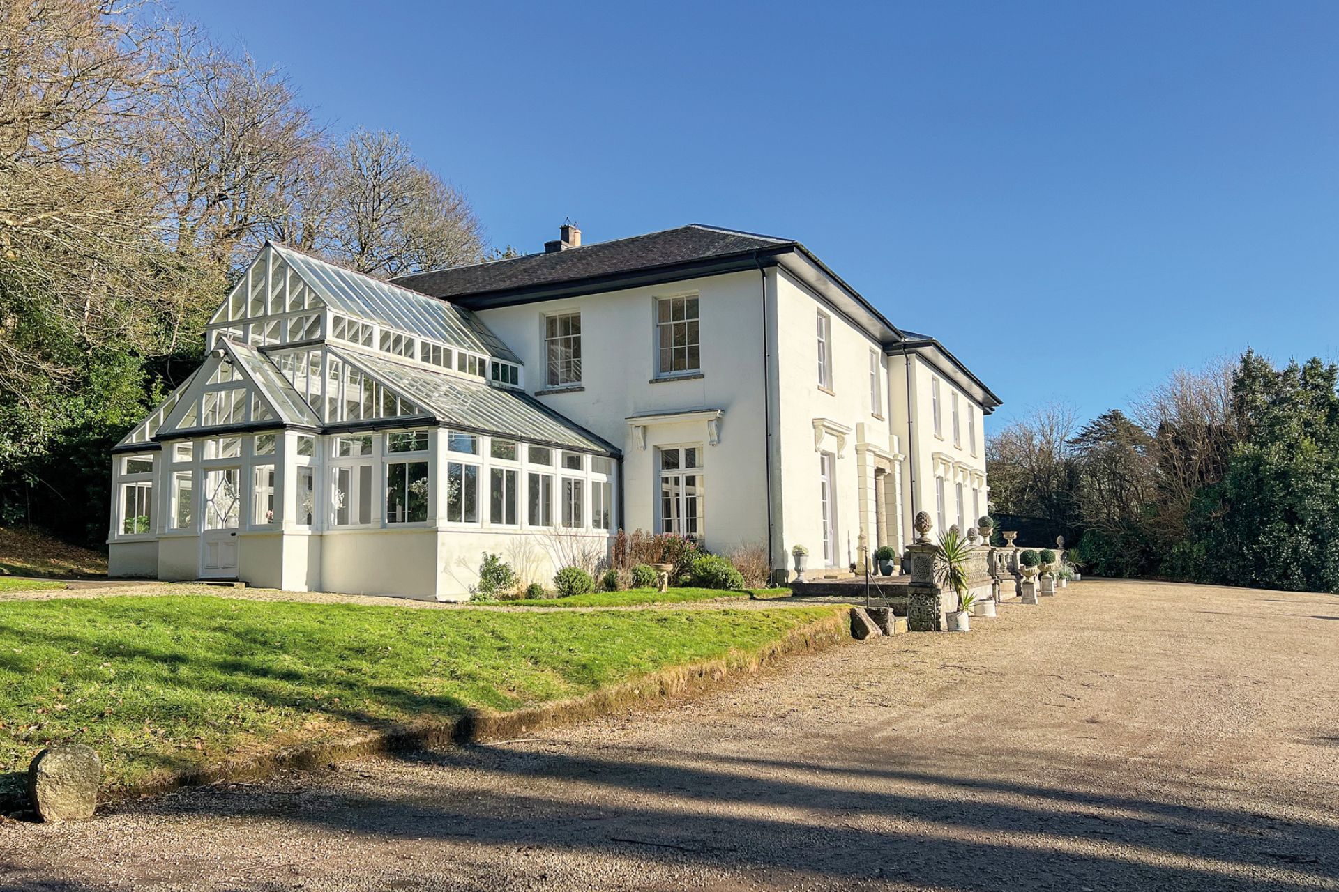 Large country home with lawns, a gravel driveway and a conservatory.