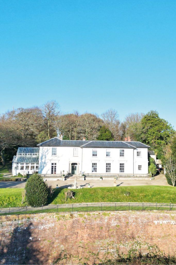 Cornish contry home with large conservatory and a stone bridge in the foreground.