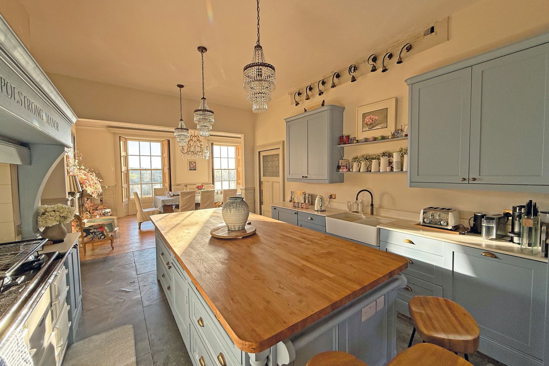 Large farmhouse-style kitchen with teal cabinets, oak countertops and a dining area.