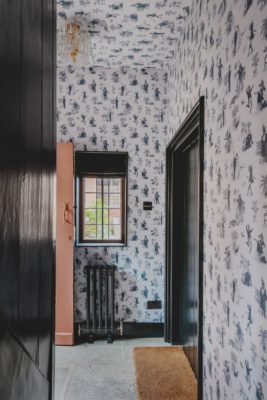 Hallway with blue and white floral wallpaper on the walls and ceiling.