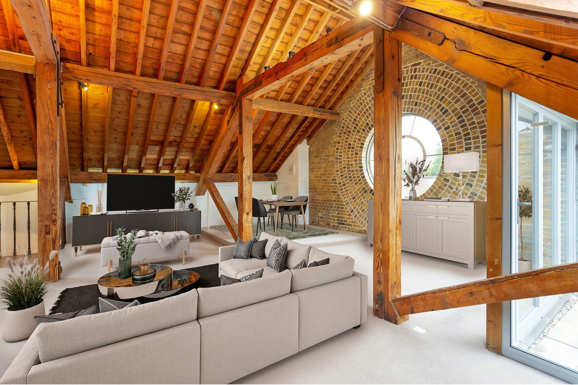 Penthouse living room with taupe modular sofas, wooden vaulted ceiling, wooden beams, and an exposed brick wall with a circular window