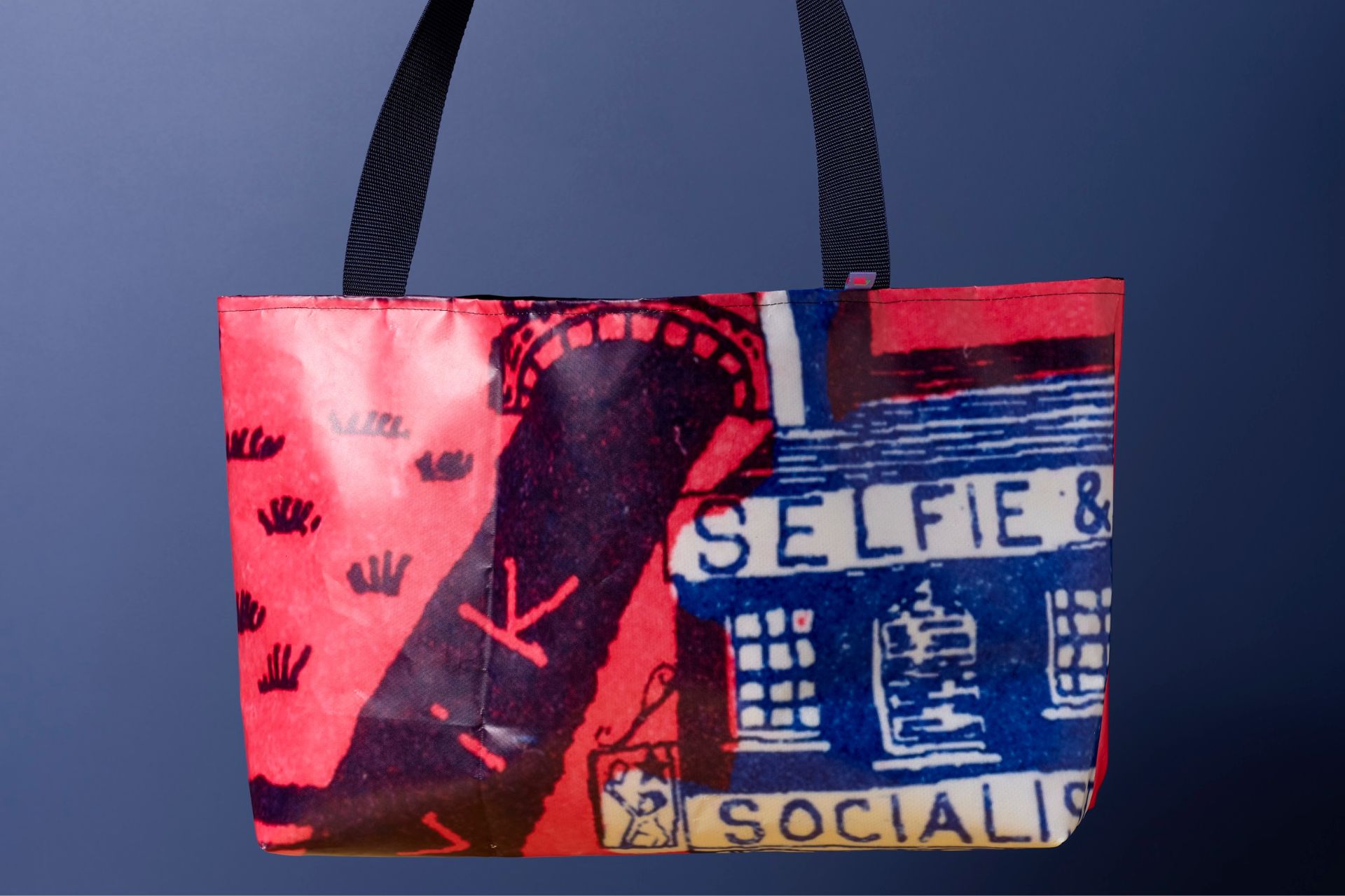 A red and black Grayson Perry-designed tote bag with black handles.