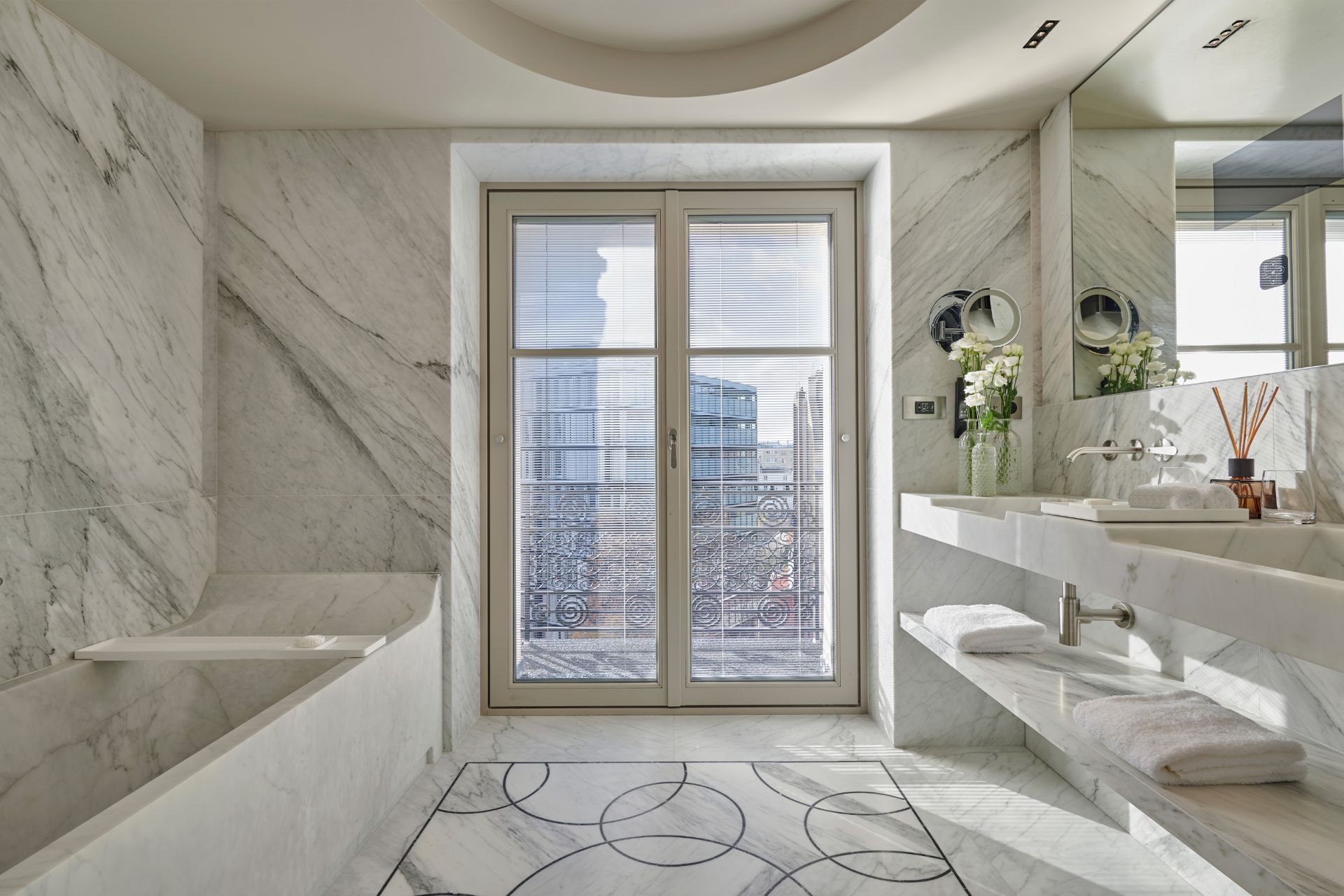 Marble bathroom with a circular design on the floors and a floor-to-ceiling window