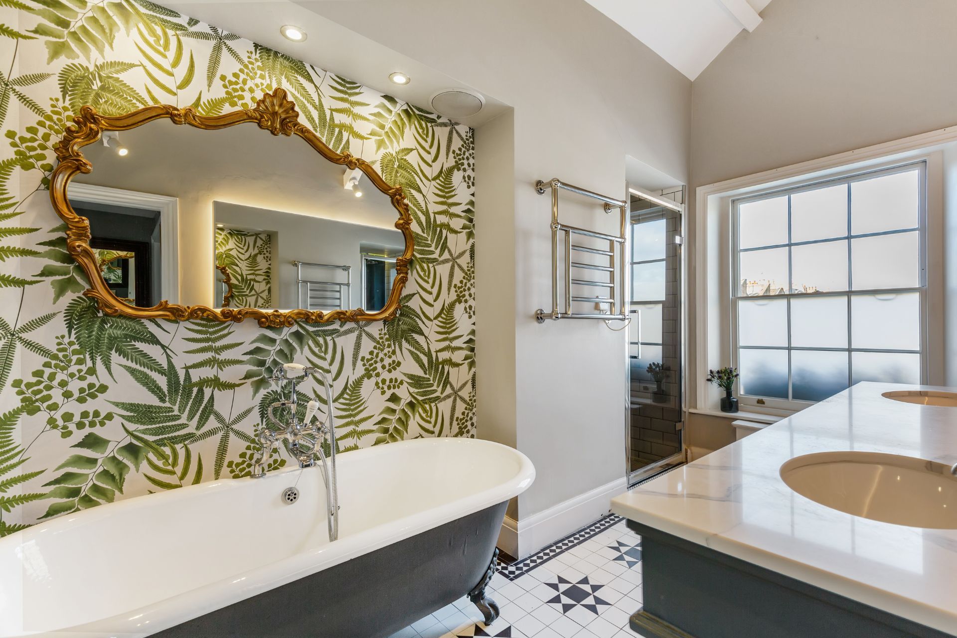 Bathroom with tiled floors, navy freestanding tub and green botanical wallpaper