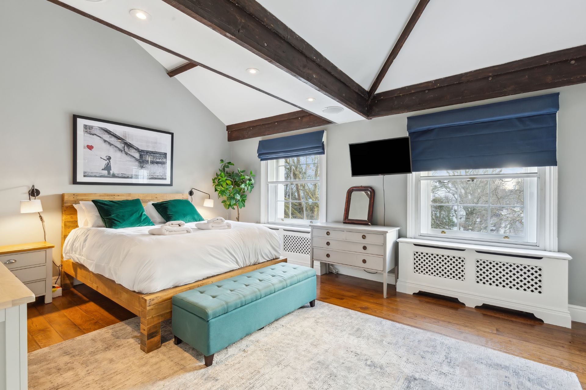 Bedroom with wooden floors, ceiling beams and navy blinds