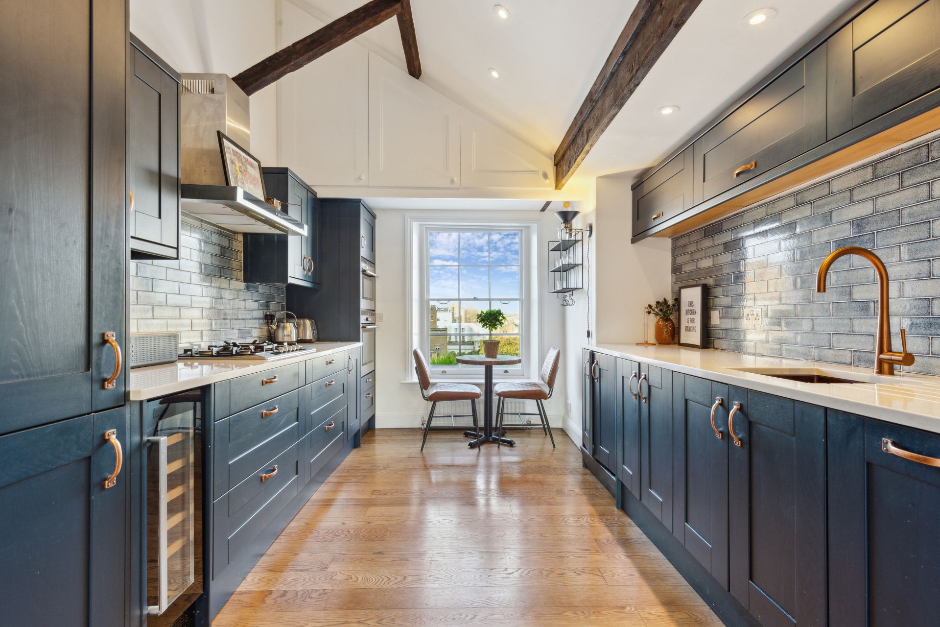 Navy blue kitchen with white worktops, gold fittings and hardwood floors
