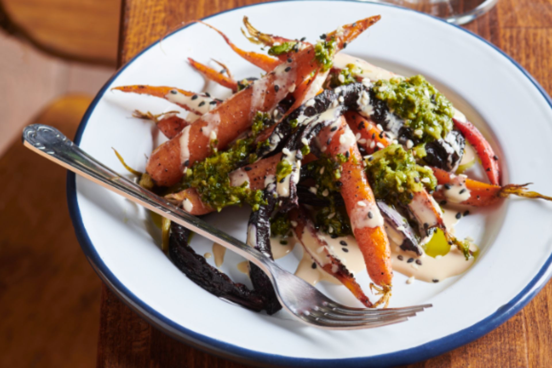 Plate of oasted carrots with herbs and a creamy dressing.