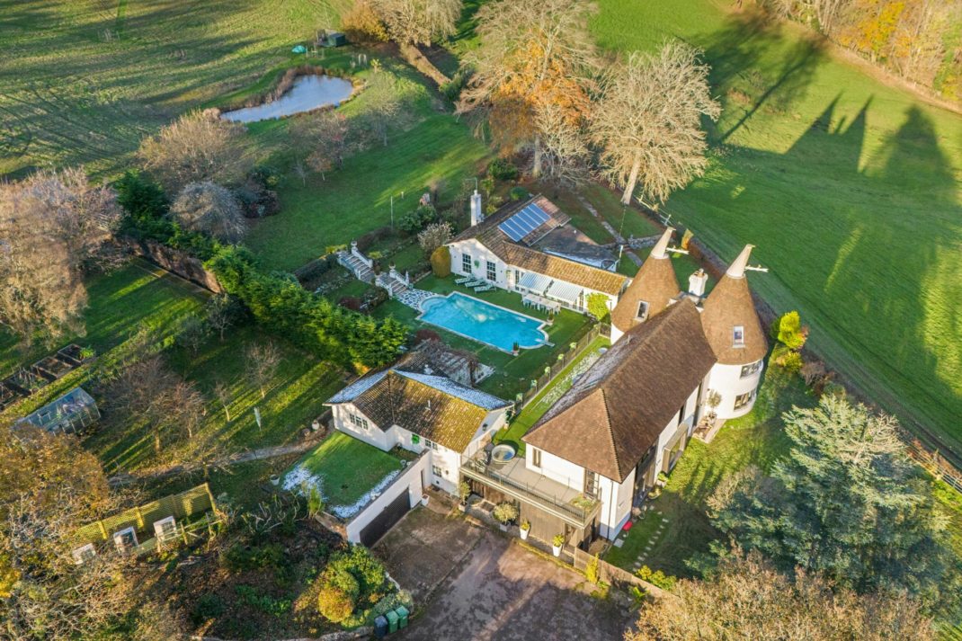 Aerial view of large oast house with a patio and outdoor pool