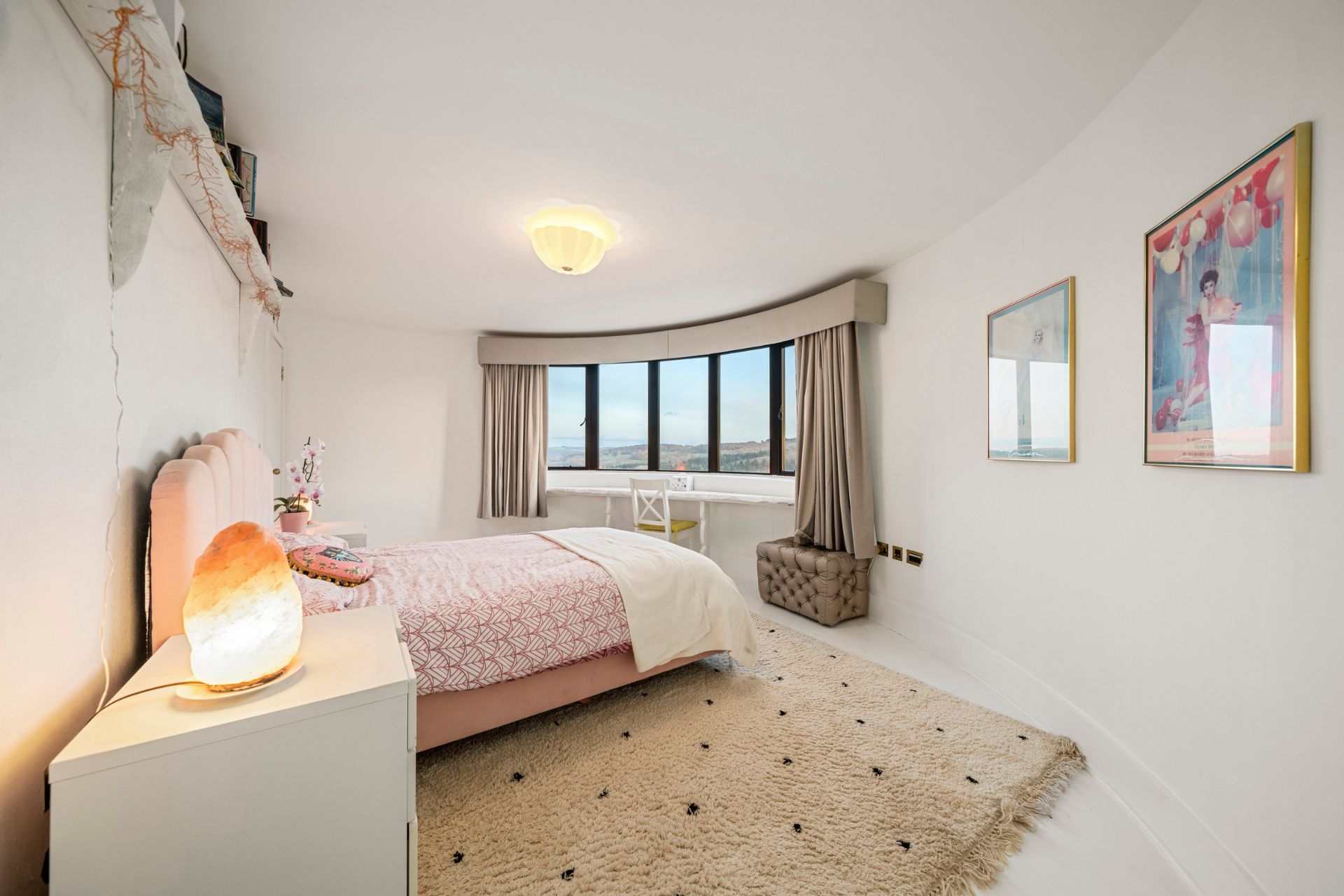 Kids' bedroom with a pale pink bedspread, beige rug and a salt lamp.