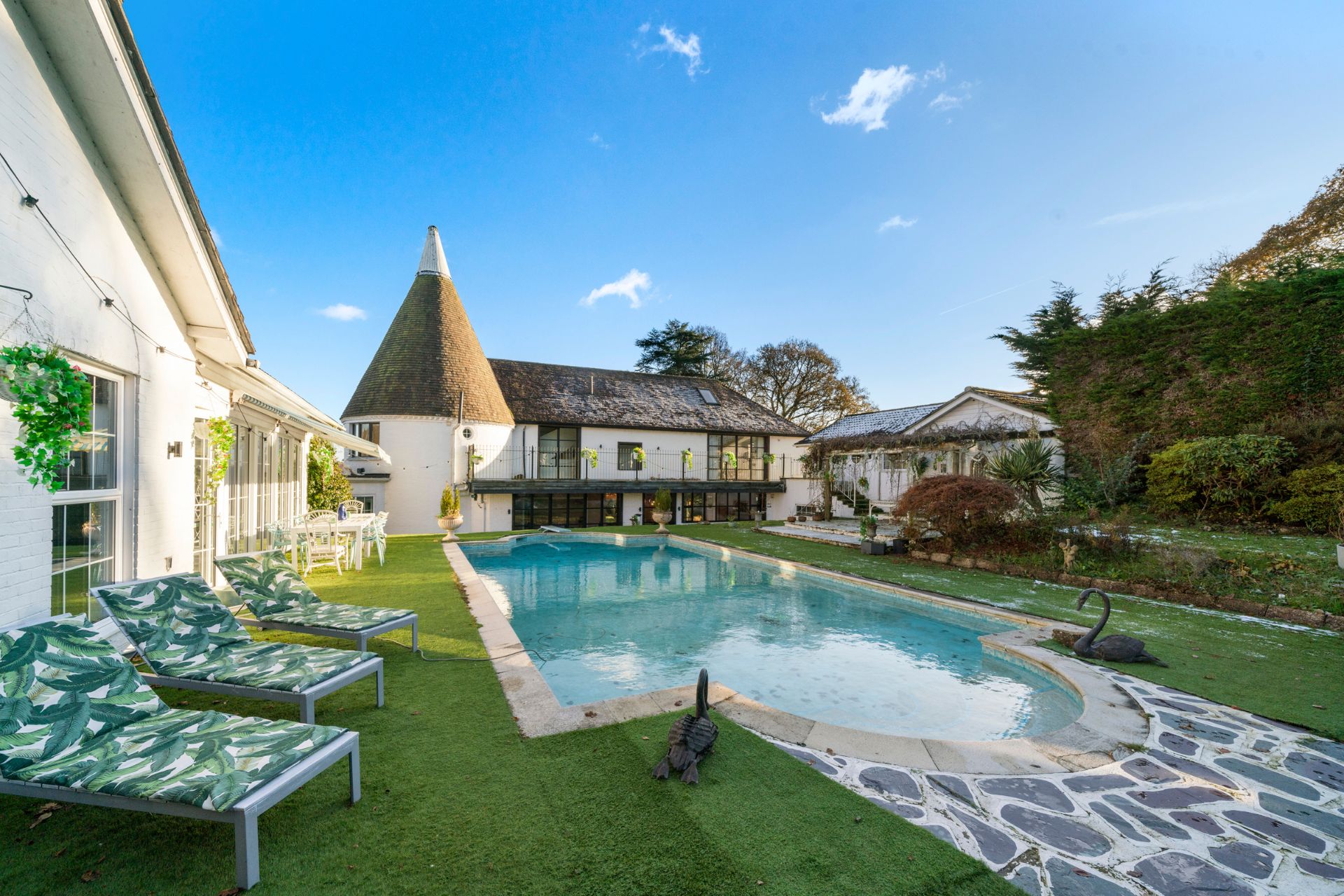 Oast house with outdoor pool, patio area, and sun loungers