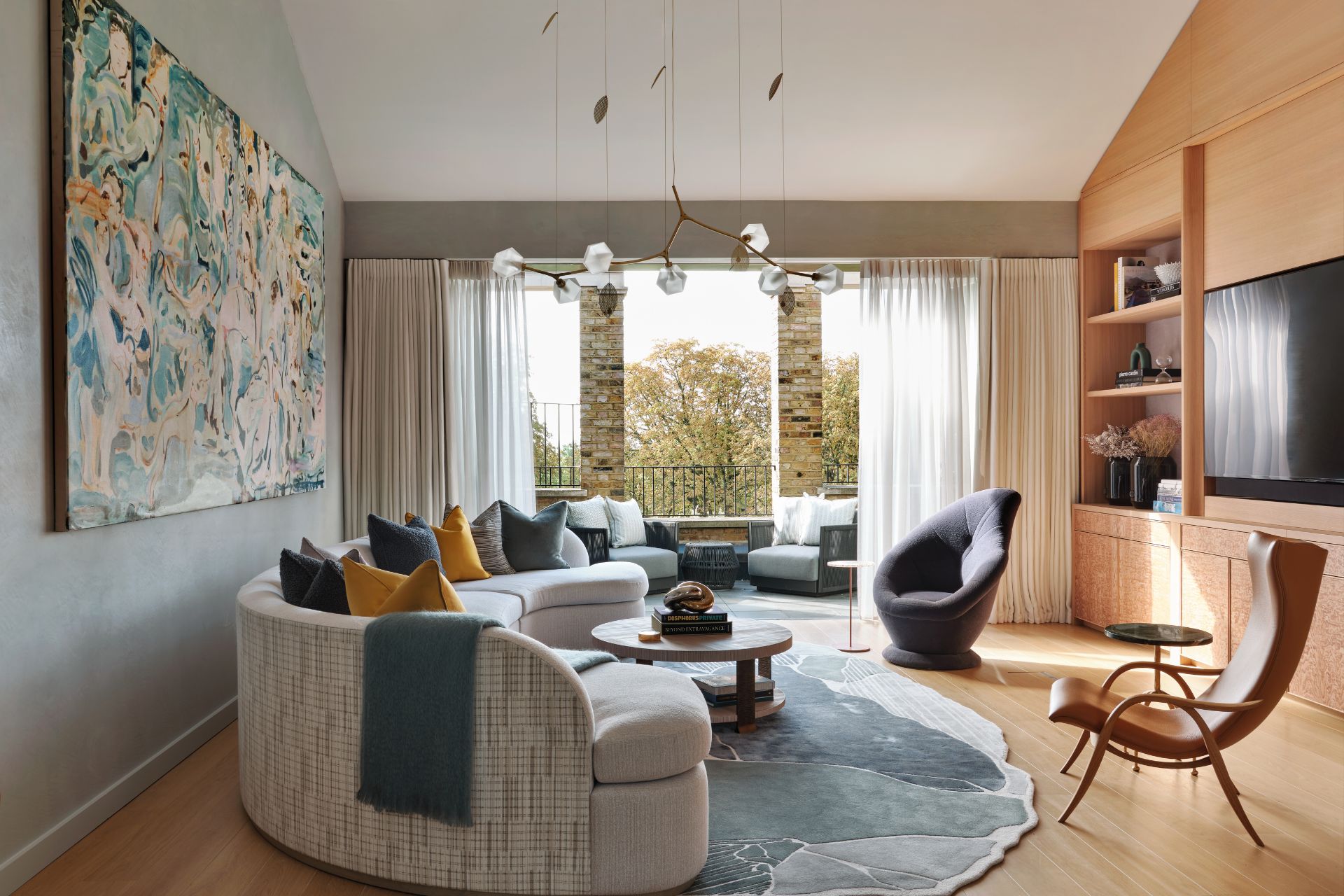 Living room with curved cream boucle sofa, a blue rug, an abstract art piece and curved blue armchairs.