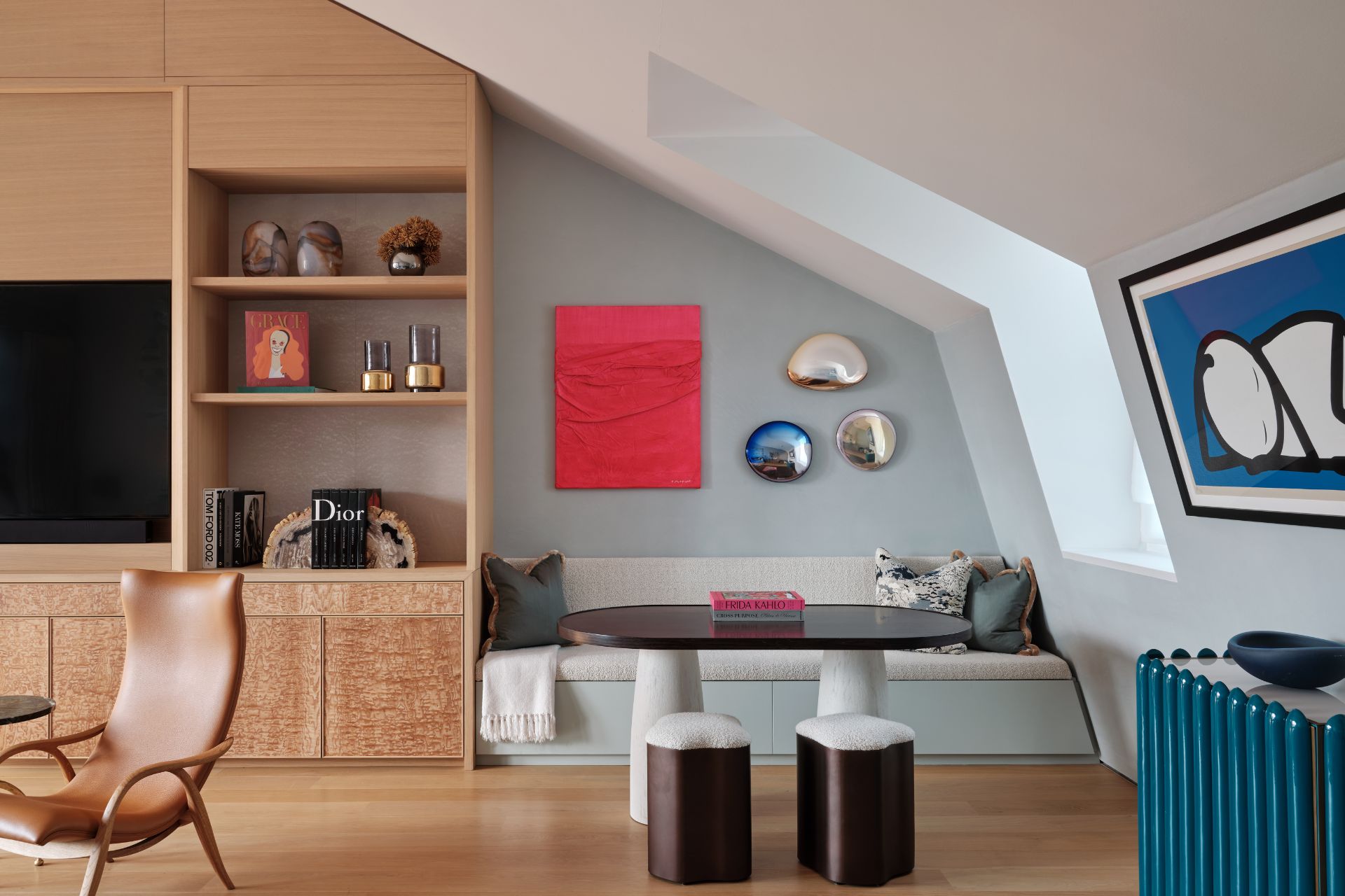 Living room with a built-in wooden media centre, brown leather armchairs, a white seating nook and royal blue accents.