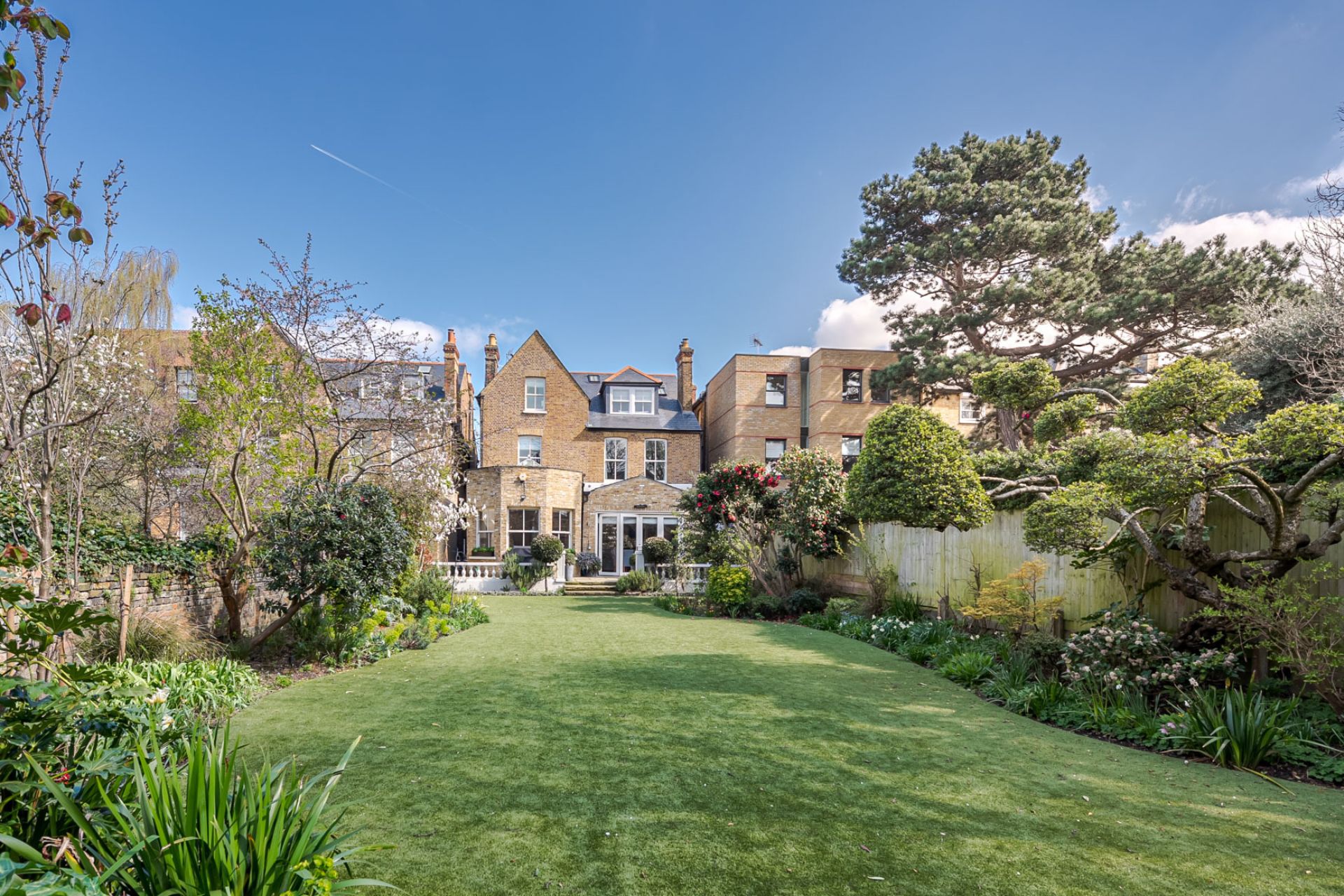 Large rear garden with a lawn and cherry blossom trees.