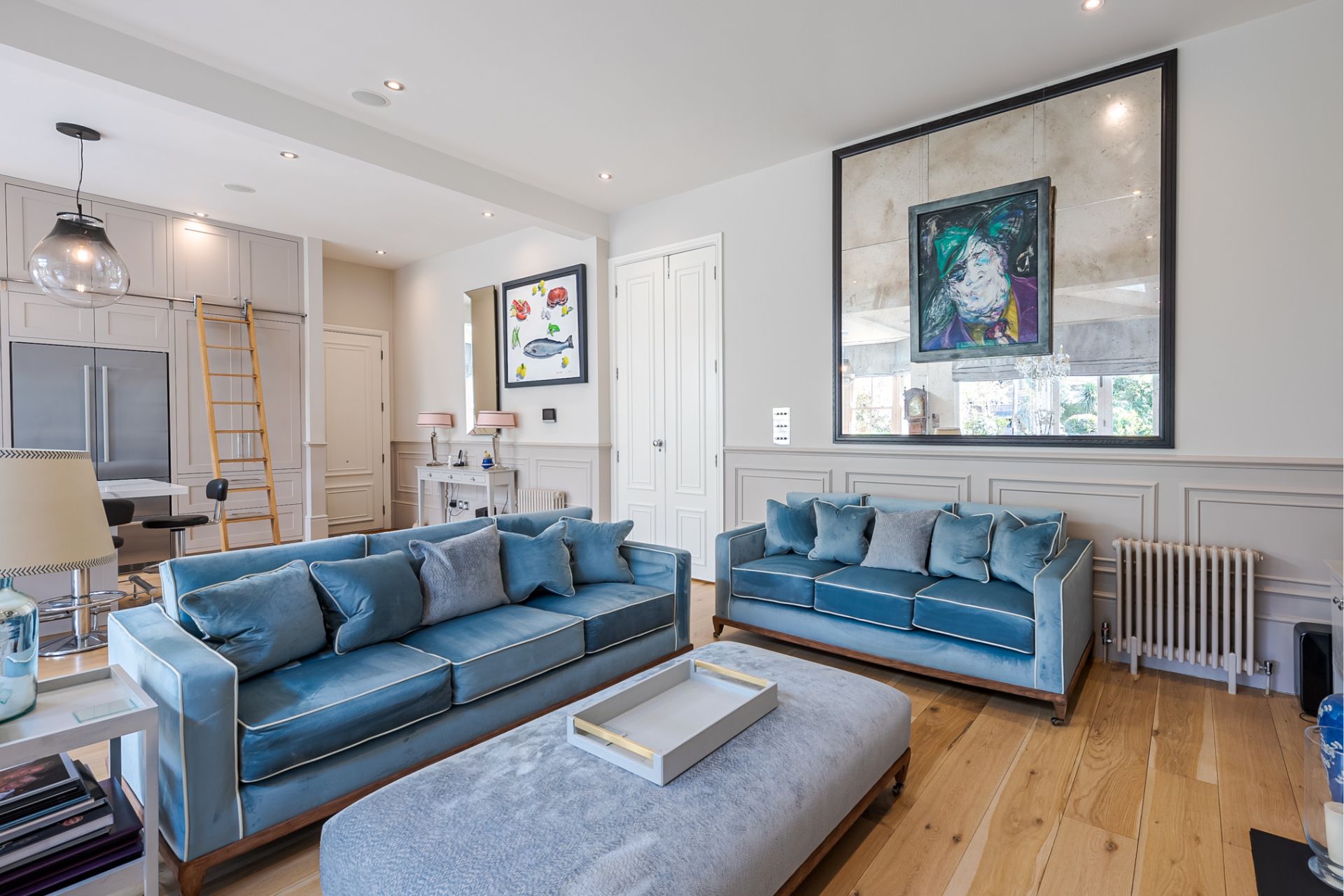 Living room with pale blue velvet sofas and wooden floors.