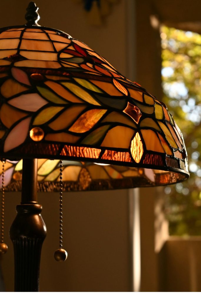 Tffany style lamp in front of an open window with forest views
