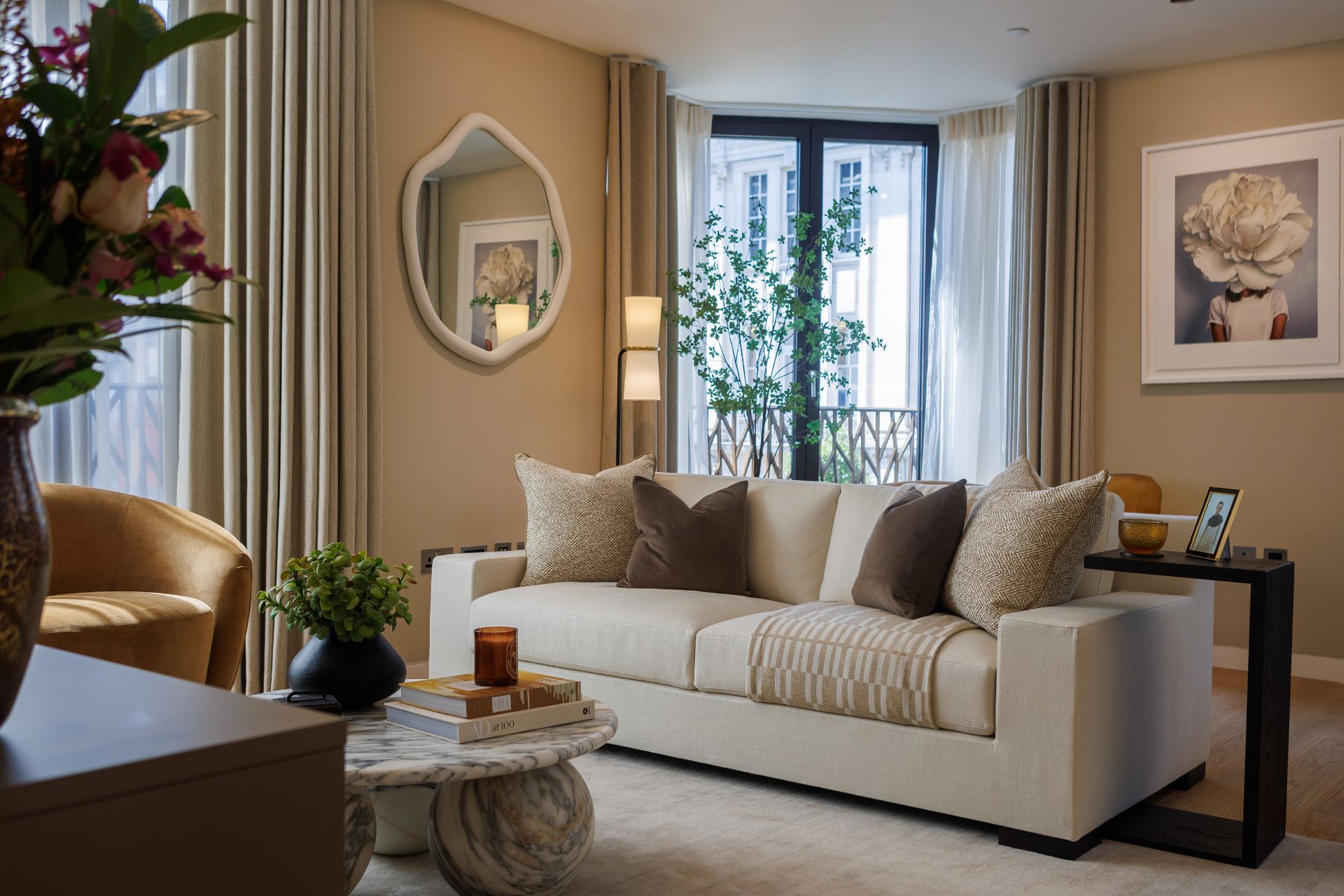 Living room with cream sofa, taupe walls, a marble coffee table and floor-to-ceiling bay windows.