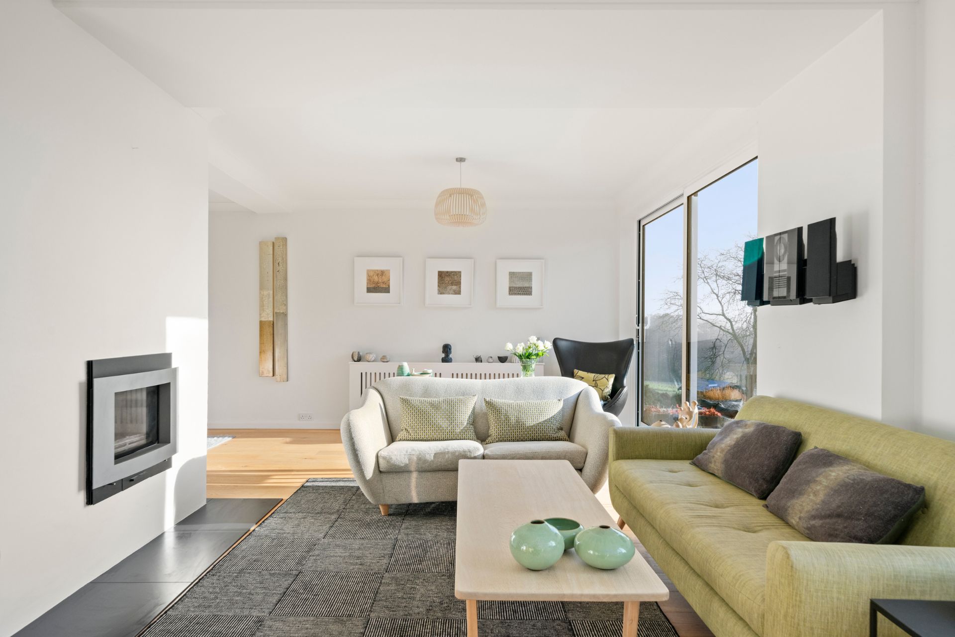 Living room with white walls, a grey rug and a pale green sofa