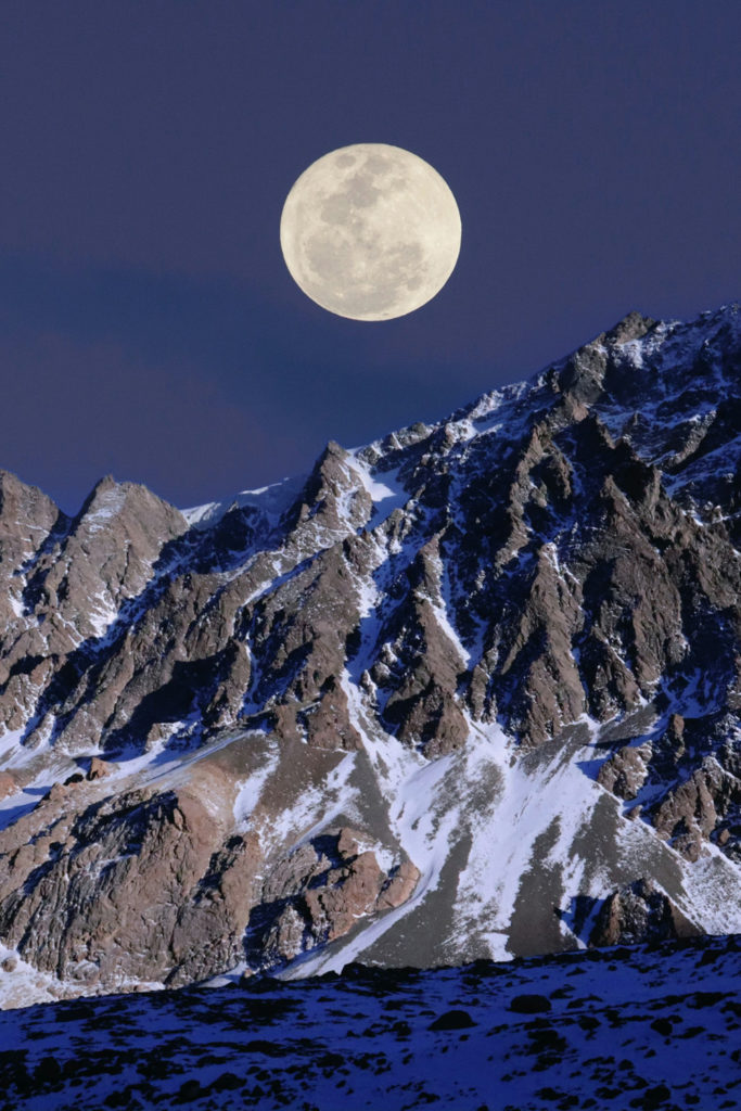 A full moon above a snowy mountain