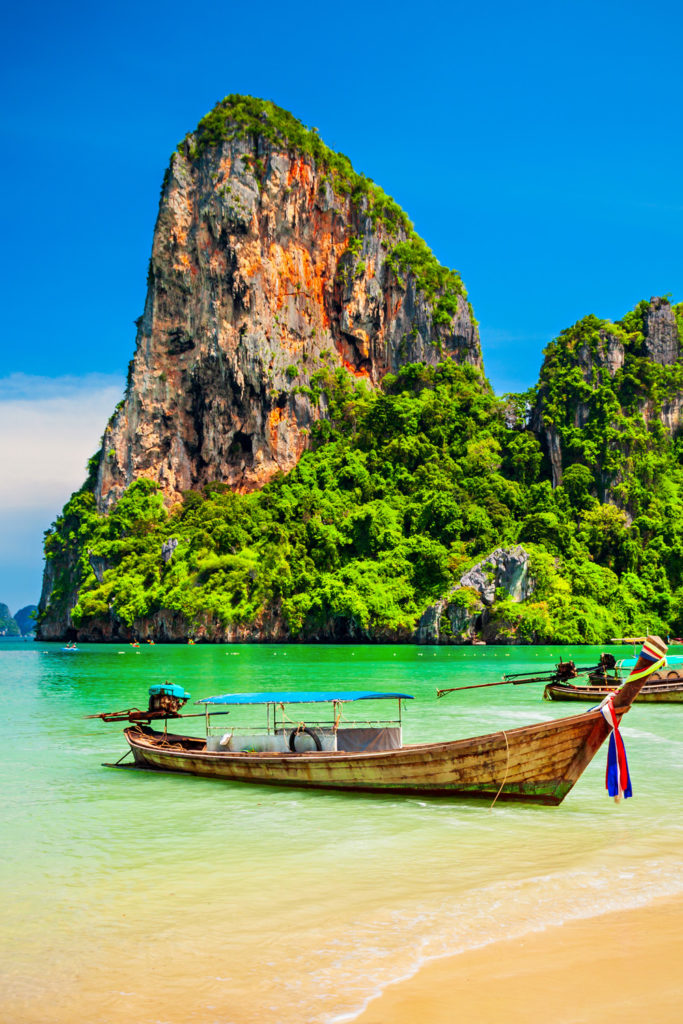 Boats at the beauty beach with limestone cliff and crystal clear water in Thailand