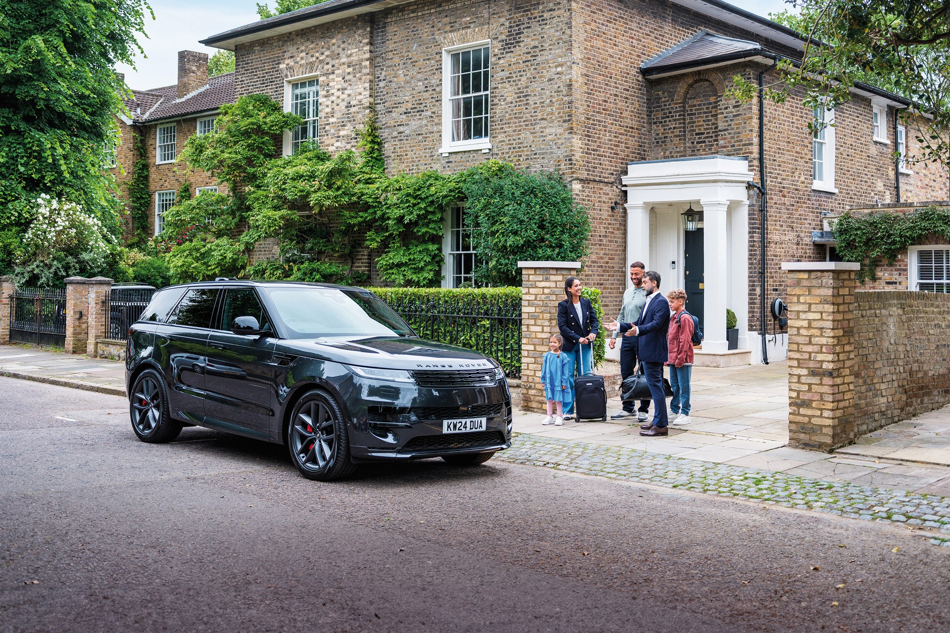 A family standing beside a luxury car