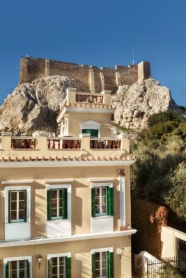 Greek mansion with green shutters, with the Acropolis rising in the background