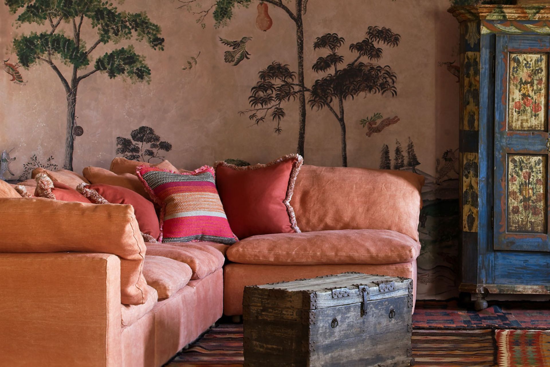 Terracotta wallpaper with palm print alongside coral pink sofa