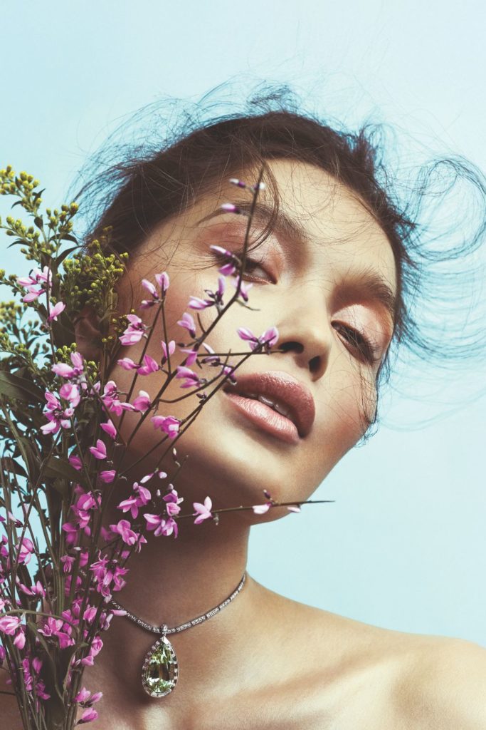 Woman against pale blue background holding a bouquet of purple flowers