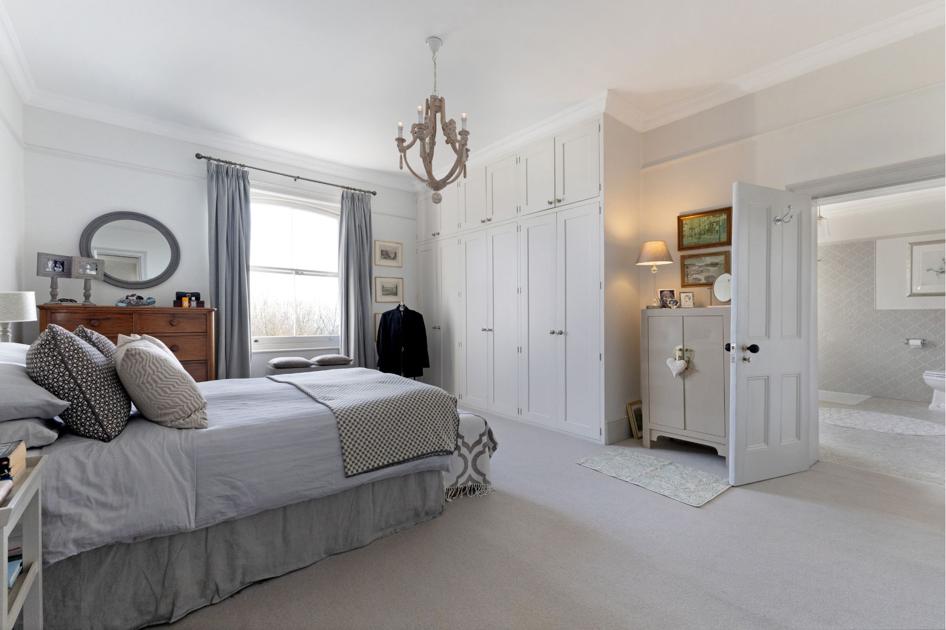 Large bedroom with cream carpets, sash windows, fitted wardrobes and an ensuite