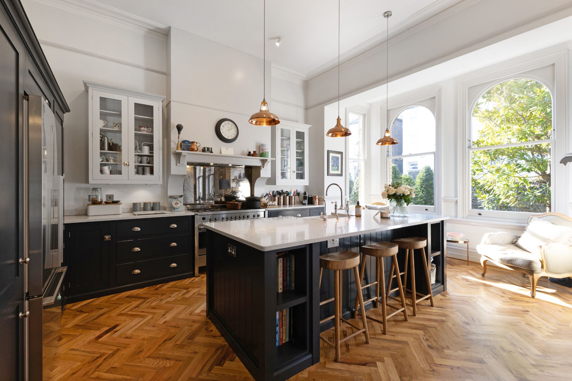 Black Sgaker kitchen with oak parquet flooring and wooden barstools