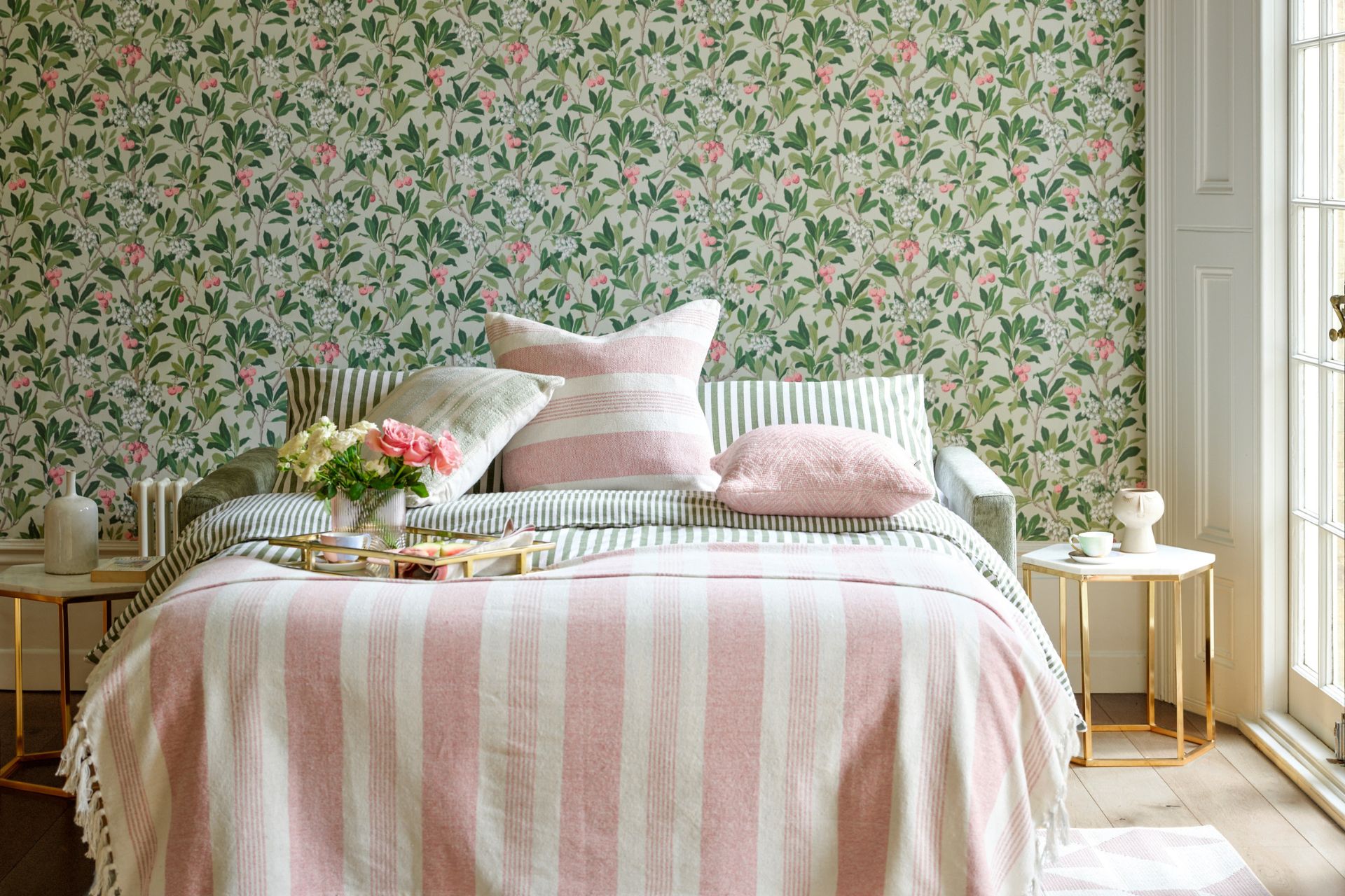 Bedroom with green floral wallpaper and a pale pink and white striped duvet set