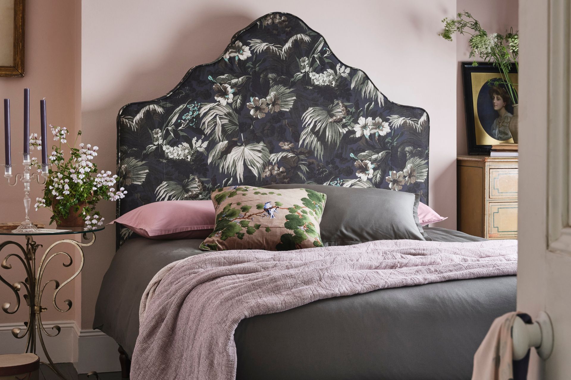 Pale pink bedroom with black floral patterned headboard and pale pink bedspread