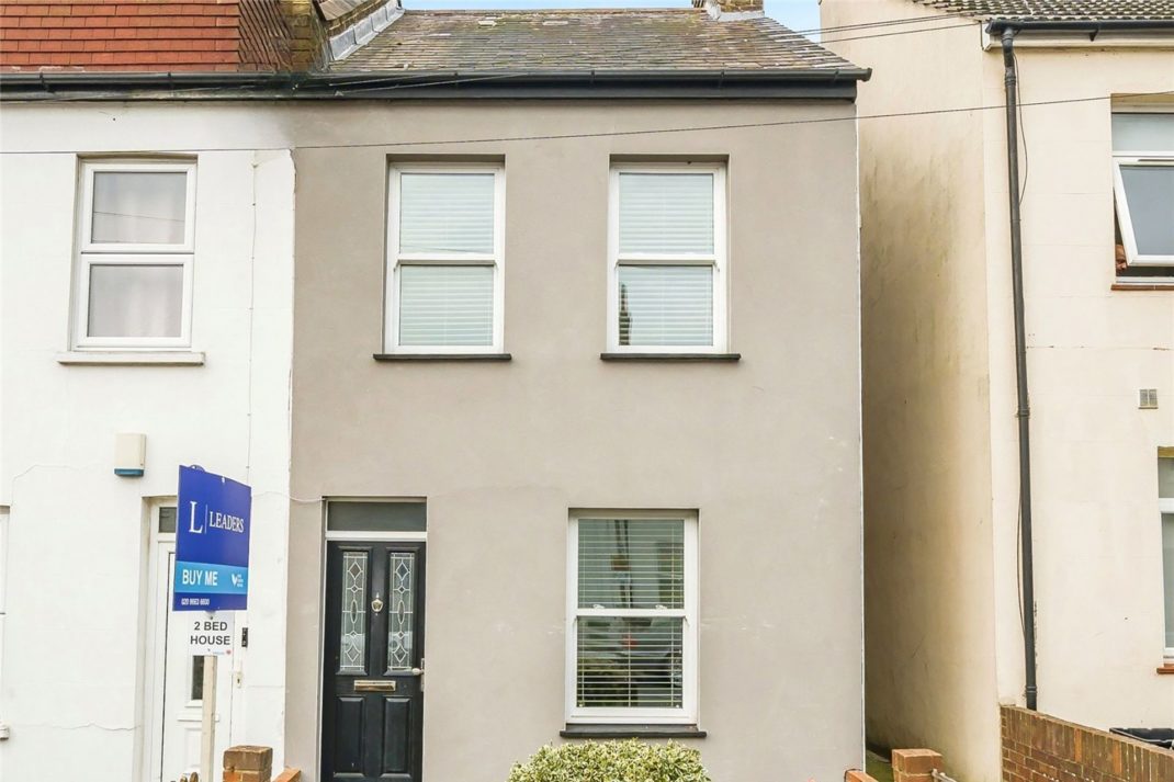 Exterior of terraced home with beige facade and a black front door