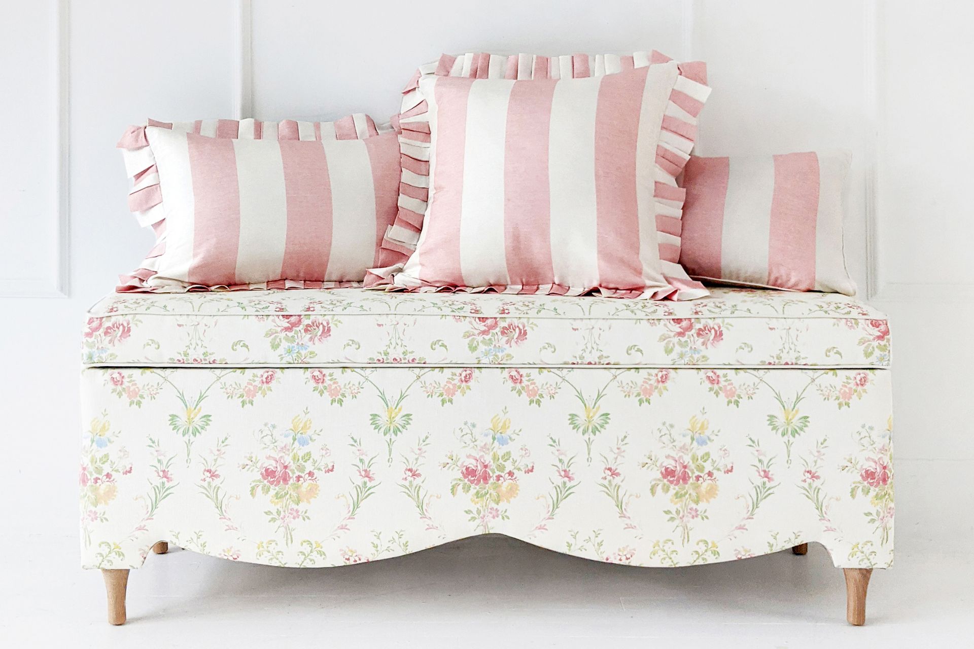 White floral ottoman with pink and white stripe ruffle cushions on top