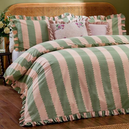 Rattan bed with green and pale pink striped bedding with a ruffled trim