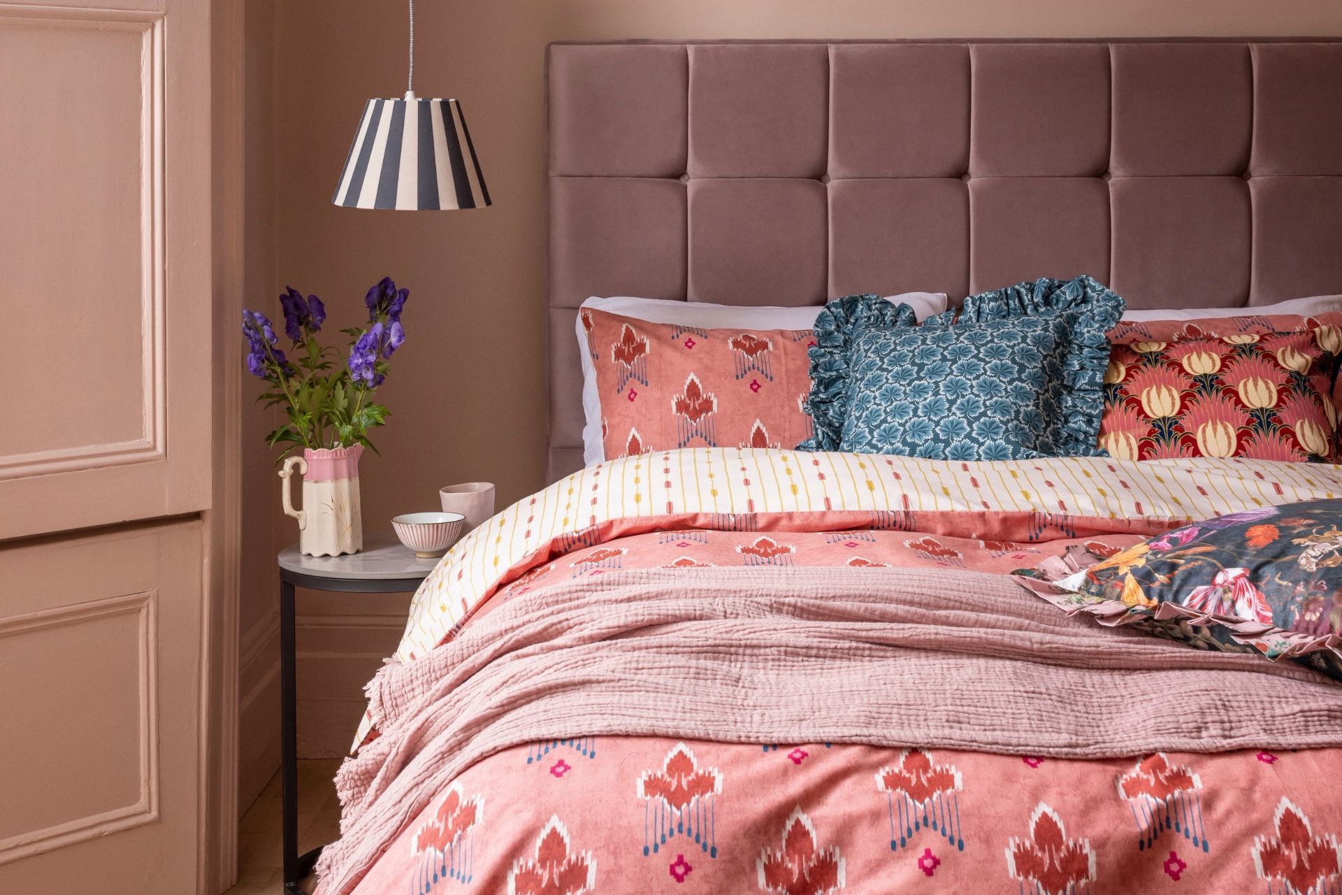 Pink floral bedding with dusky purple bedframe and dusky pink walls