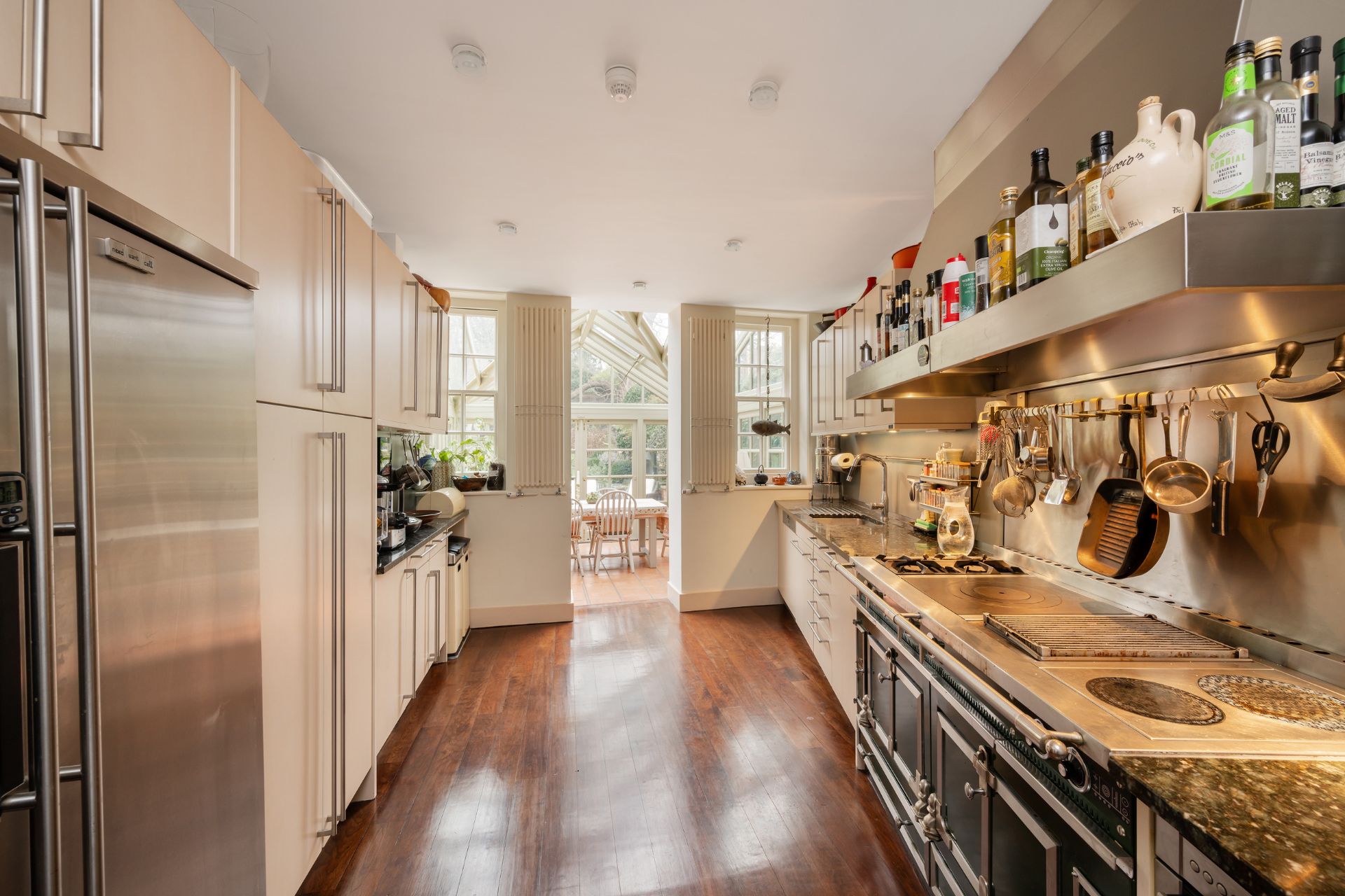 Galley kitchen with white Shaker cabinets, a black range cooker, and a conservatory dining area