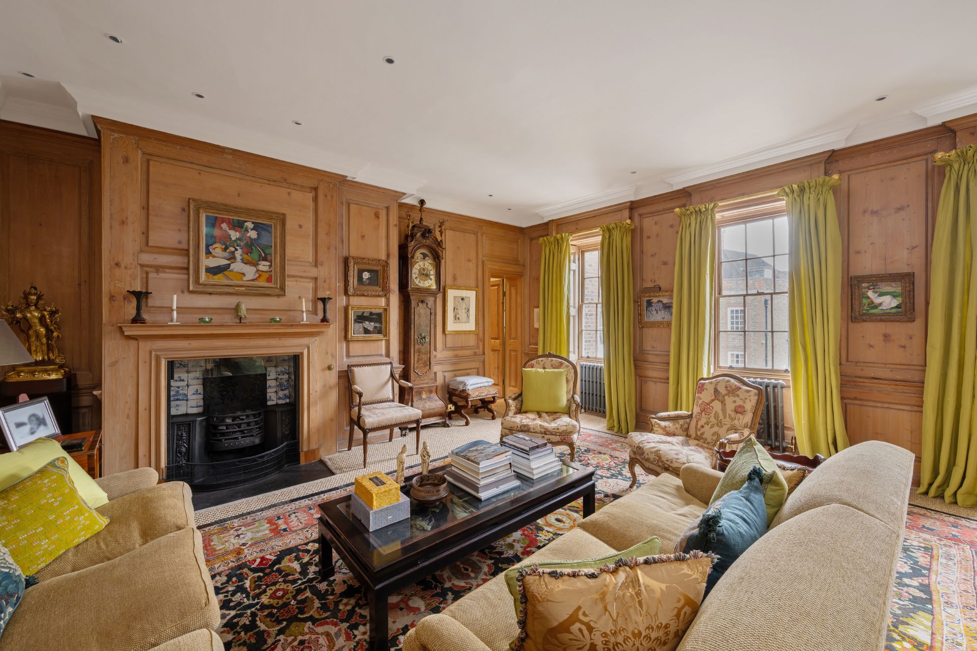 Wood-panelled living room with cream armchairs, acid yellow accents, and a large fireplace