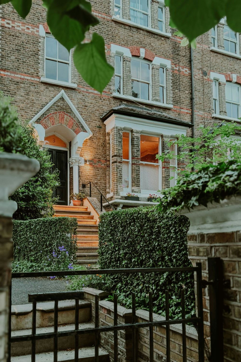 Pale brick townhouse in Hampstead with landscape hedging and wrought iron railings